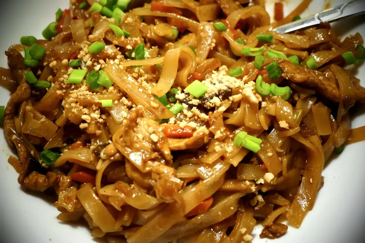 Pyszny makaron ryżowy z sosem, posypany orzeszkami ziemnymi i szczypiorkiem. Idealny na szybki obiad.