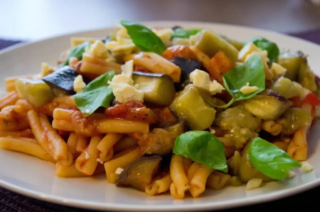 Pyszne danie z makaronem, bakłażanem i pomidorami, posypane serem i bazylią. Idealne na Pasta alla Norma przepis.