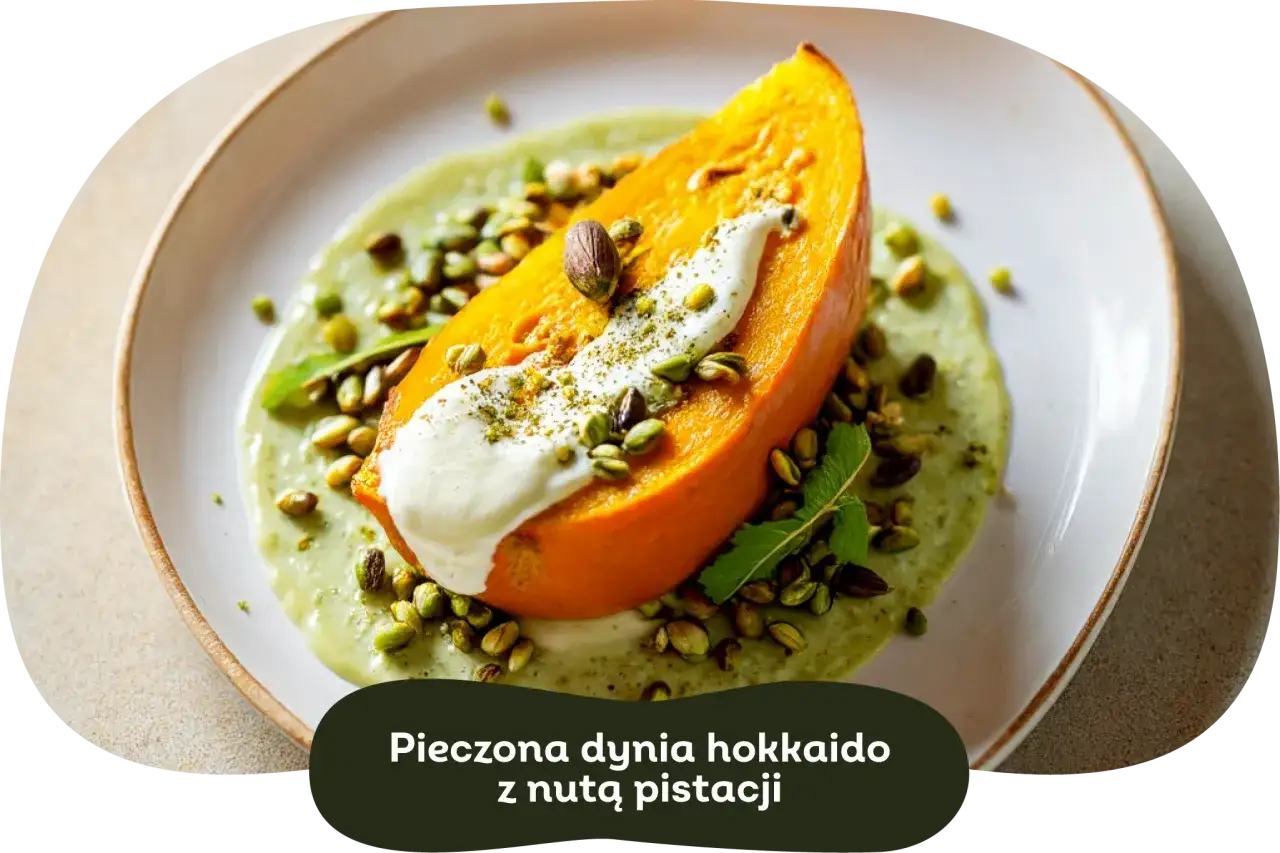 Pieczona dynia hokkaido, podana na kremowym sosie z pistacjami, ozdobiona listkami mięty.