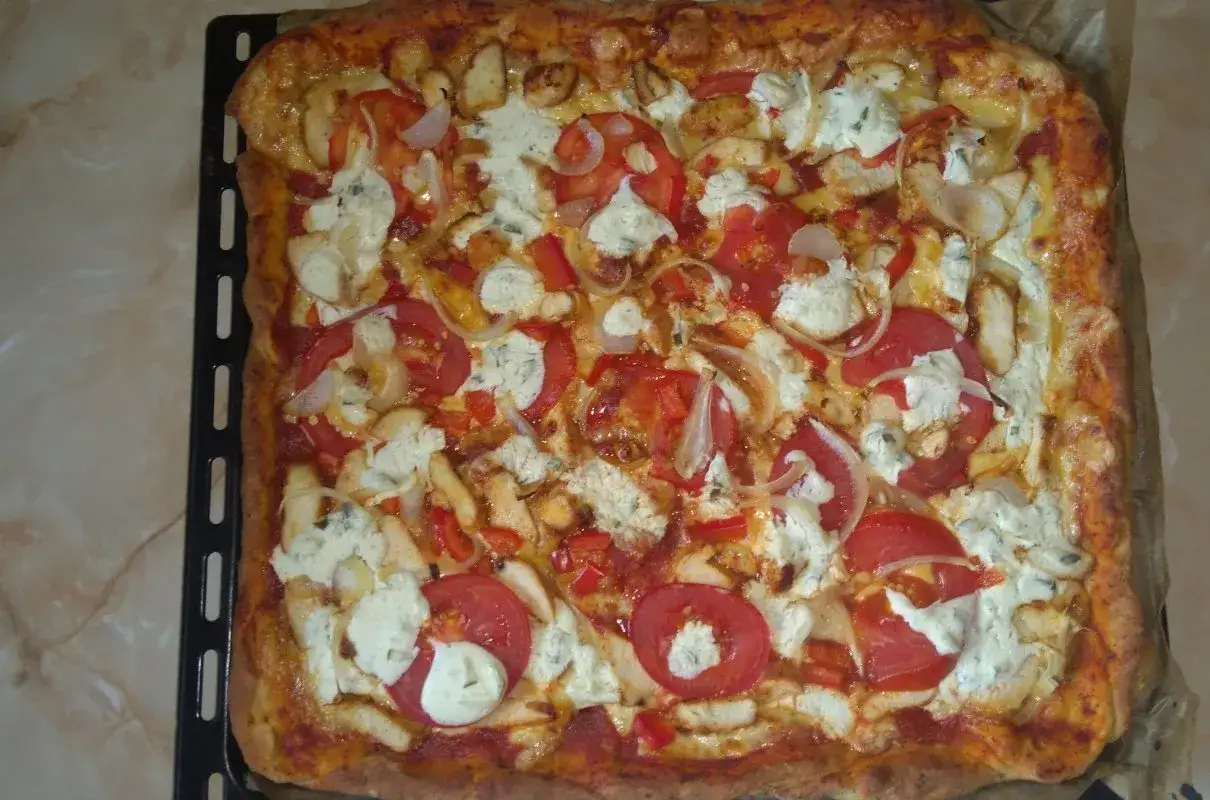 Pyszna, prostokątna pizza bez drożdży z kurczakiem, pomidorami, cebulą i serem.