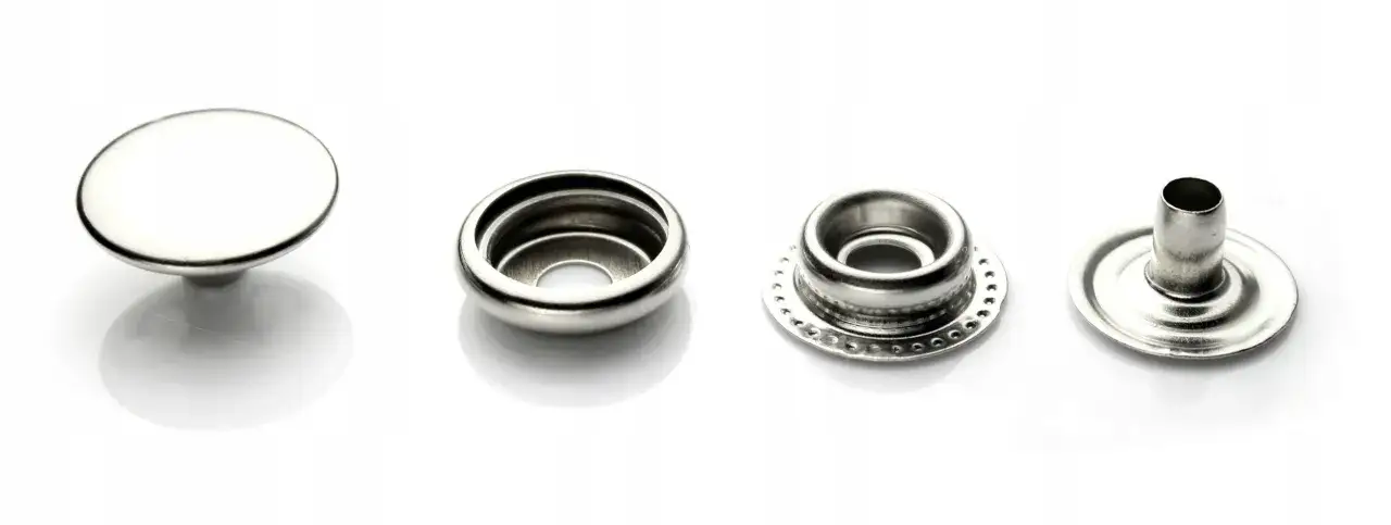 Metalowe napy, czyli rodzaje zapięć w ubraniach, pokazane w czterech częściach: główka, gniazdo, pierścień i trzpień.