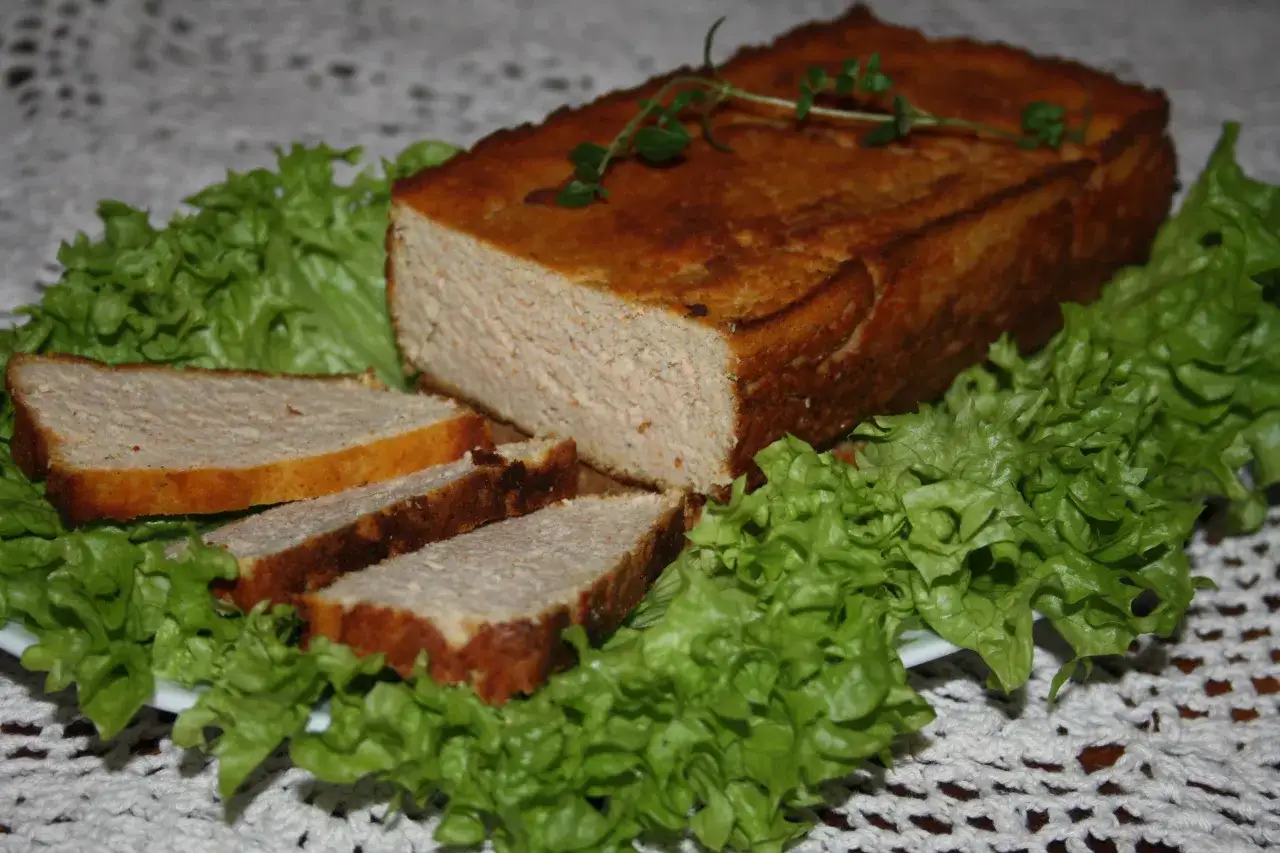 Pyszny pasztet drobiowy z wątróbką, pokrojony w plastry, podany na liściach sałaty. Idealny na kanapki.