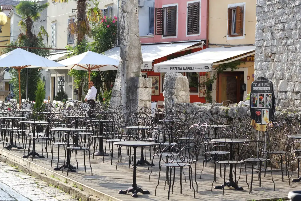 Letni dzień na półwyspie Istria. Pusta kawiarnia z czarnymi, metalowymi stolikami i krzesłami czeka na gości.