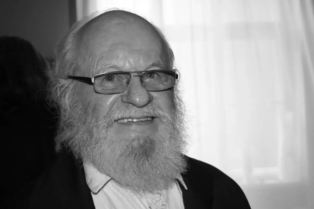 Uśmiechnięty Aleksander Skowroński z siwą brodą i okularami.