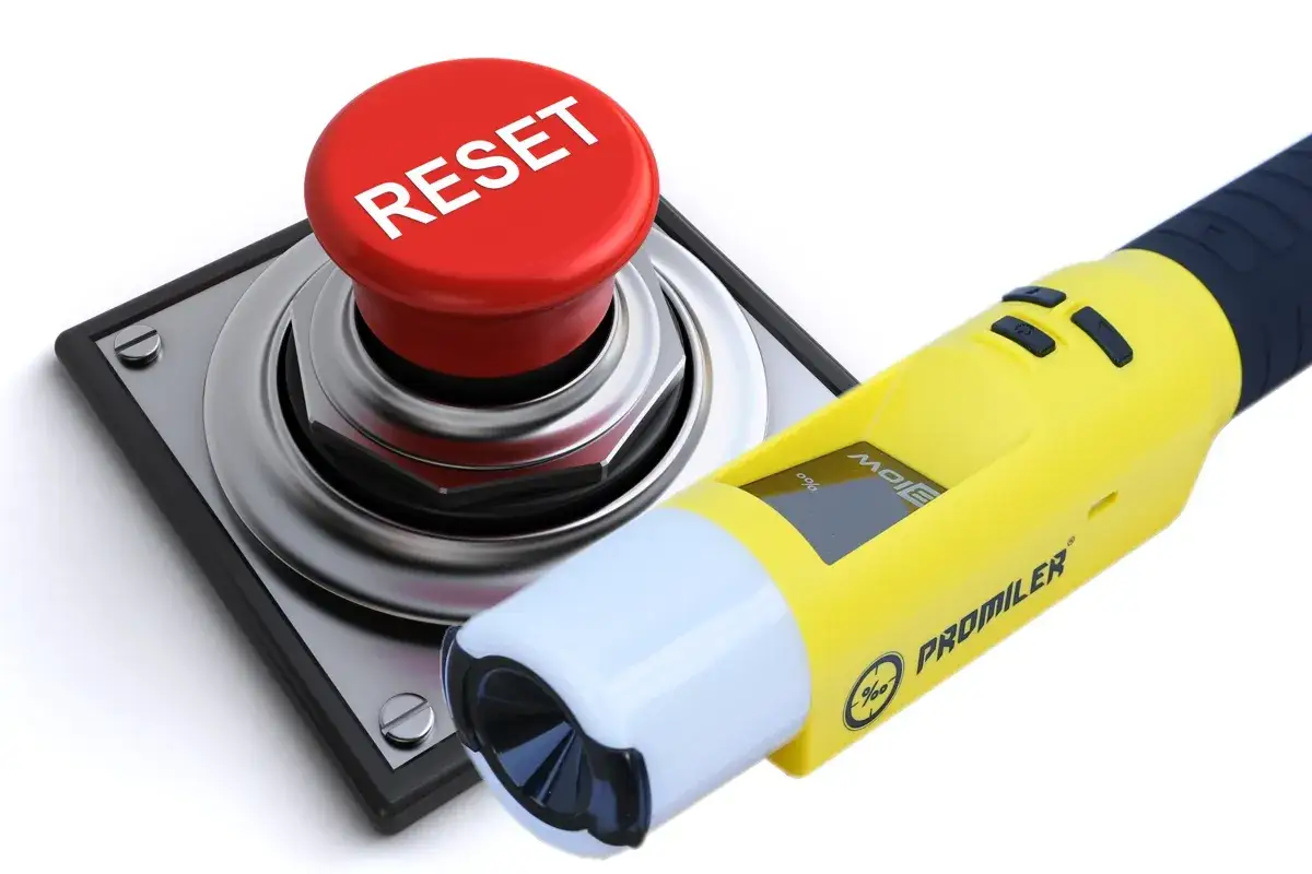 Żółty alkomat Promiler obok czerwonego przycisku RESET.