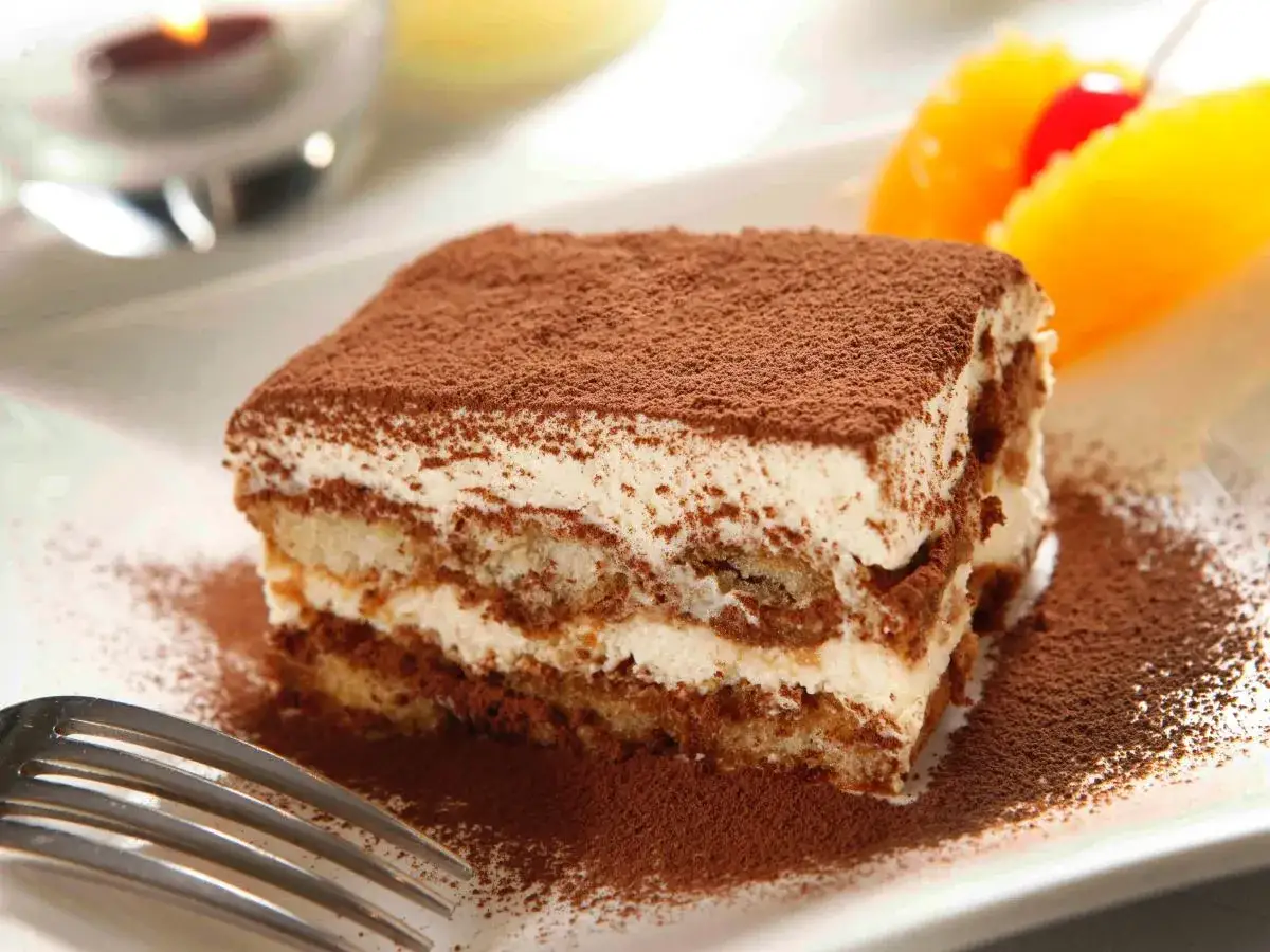 Pyszne tiramisu Ani Starmach, posypane kakao, z owocami i wisienką. Idealne na deser.