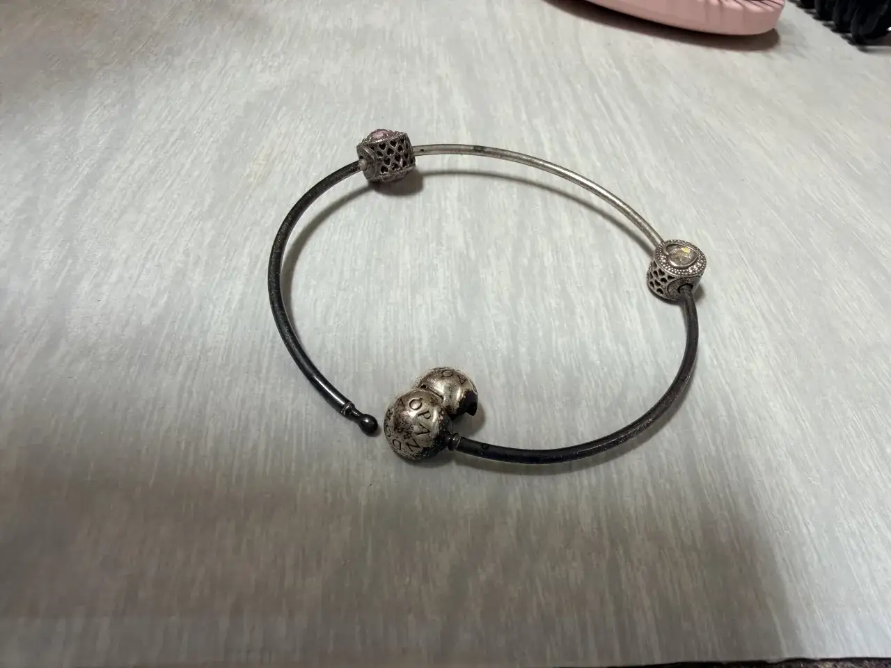 Srebrna bransoletka Pandora z charmsami, która z czasem może żółknąć z powodu reakcji chemicznych.