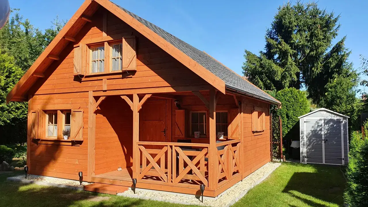 Drewniany domek na zgłoszenie, idealny na wynajem. Otoczony zielenią, z werandą i schowkiem.