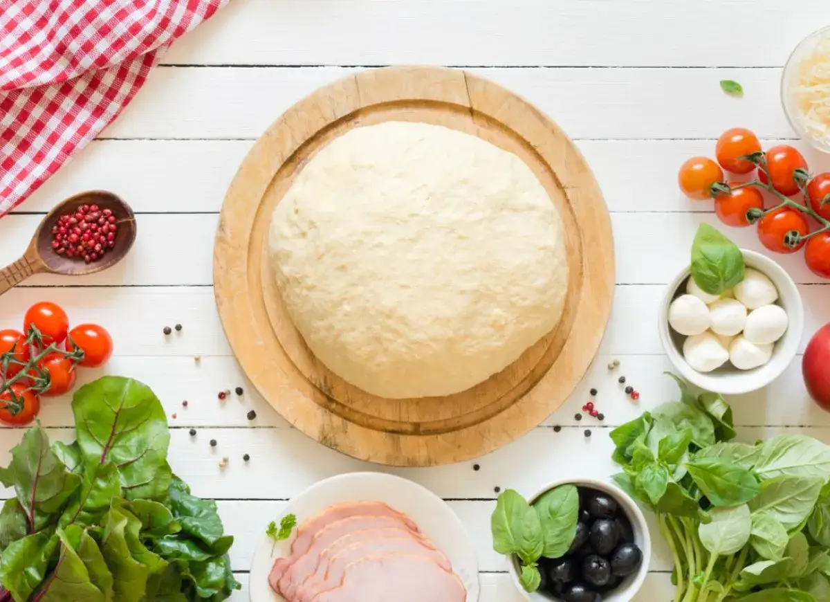 Świeże ciasto na pizzę, pomidorki, mozzarella, oliwki i szynka. Zastanawiasz się, ile może leżeć ciasto na pizzę w lodówce?