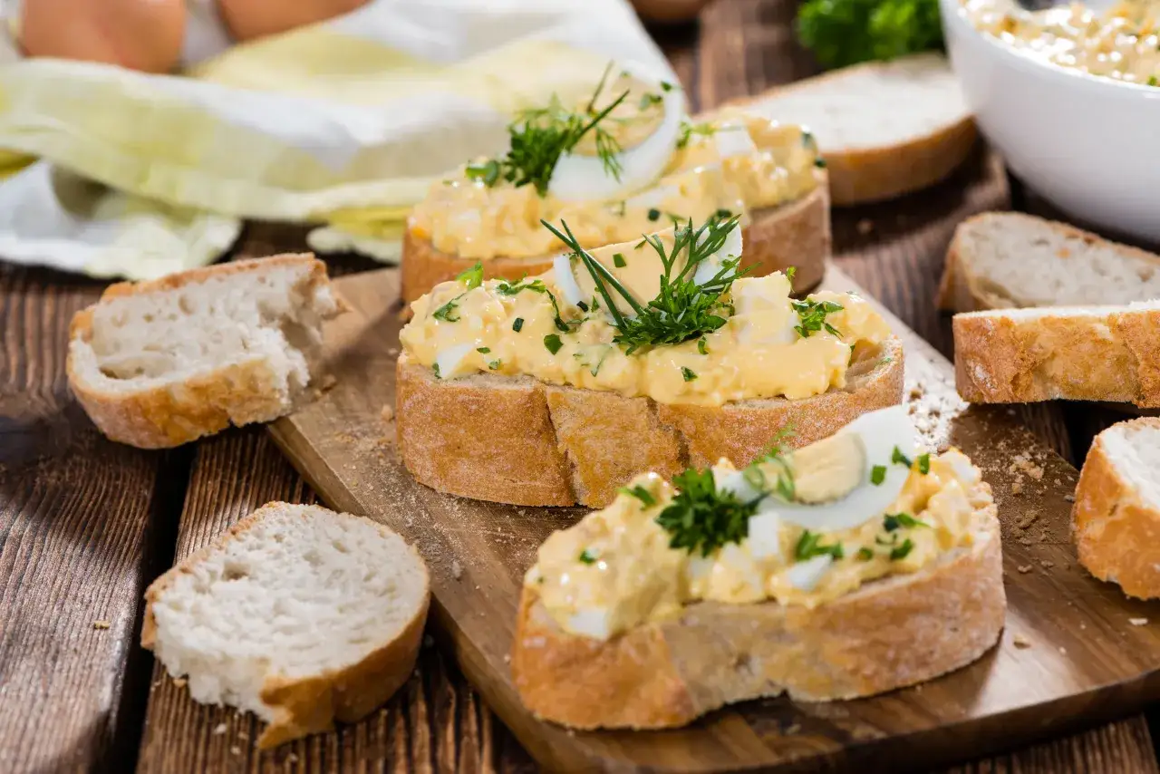 Kromki chleba z kremową pastą jajeczną na różne sposoby, ozdobione ziołami. Idealne na szybkie śniadanie lub przekąskę.