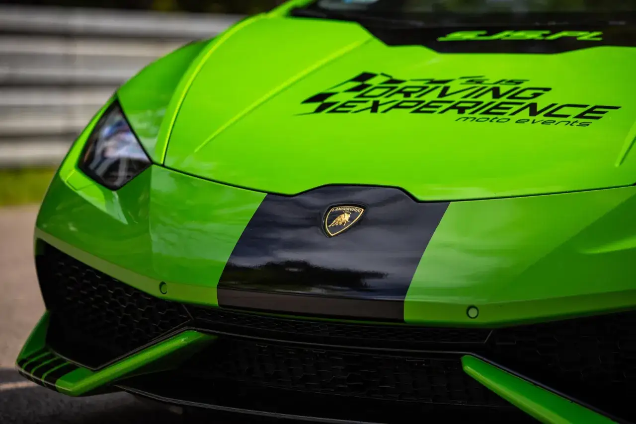 Przód zielonego Lamborghini Huracan z czarnym pasem i logo.