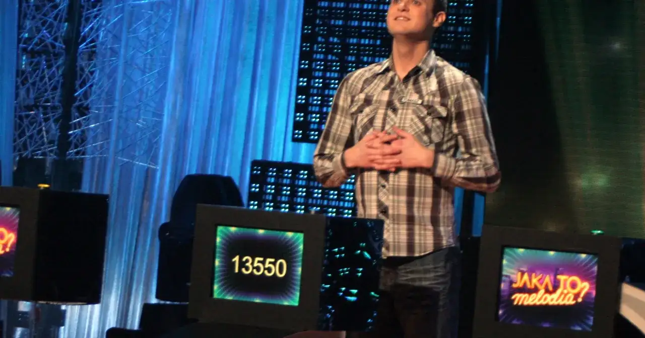 Mężczyzna w kratę, potencjalny rekordzista w "Jaka to melodia?", z dłońmi złożonymi na brzuchu. Na ekranie widnieje wynik 13550.