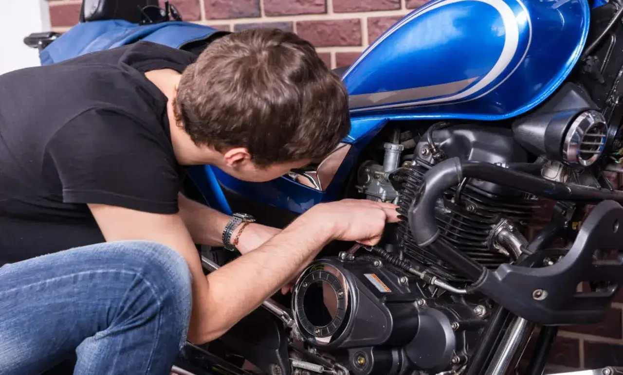 Mężczyzna naprawia niebieski motocykl. Czy to CBS?