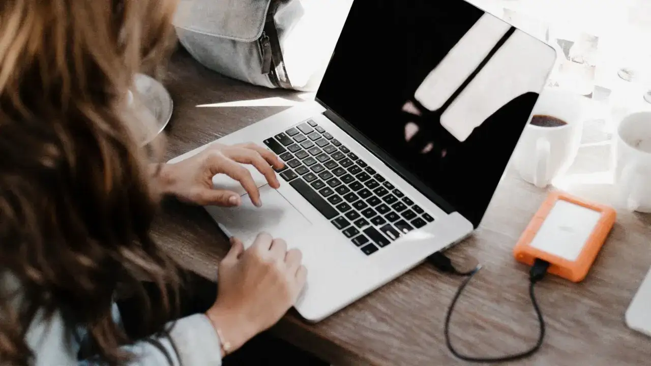 Kobieta pracuje na laptopie, szukając sposobów, jak bezpiecznie ukryć przed obecnym szefem szukanie nowej pracy.