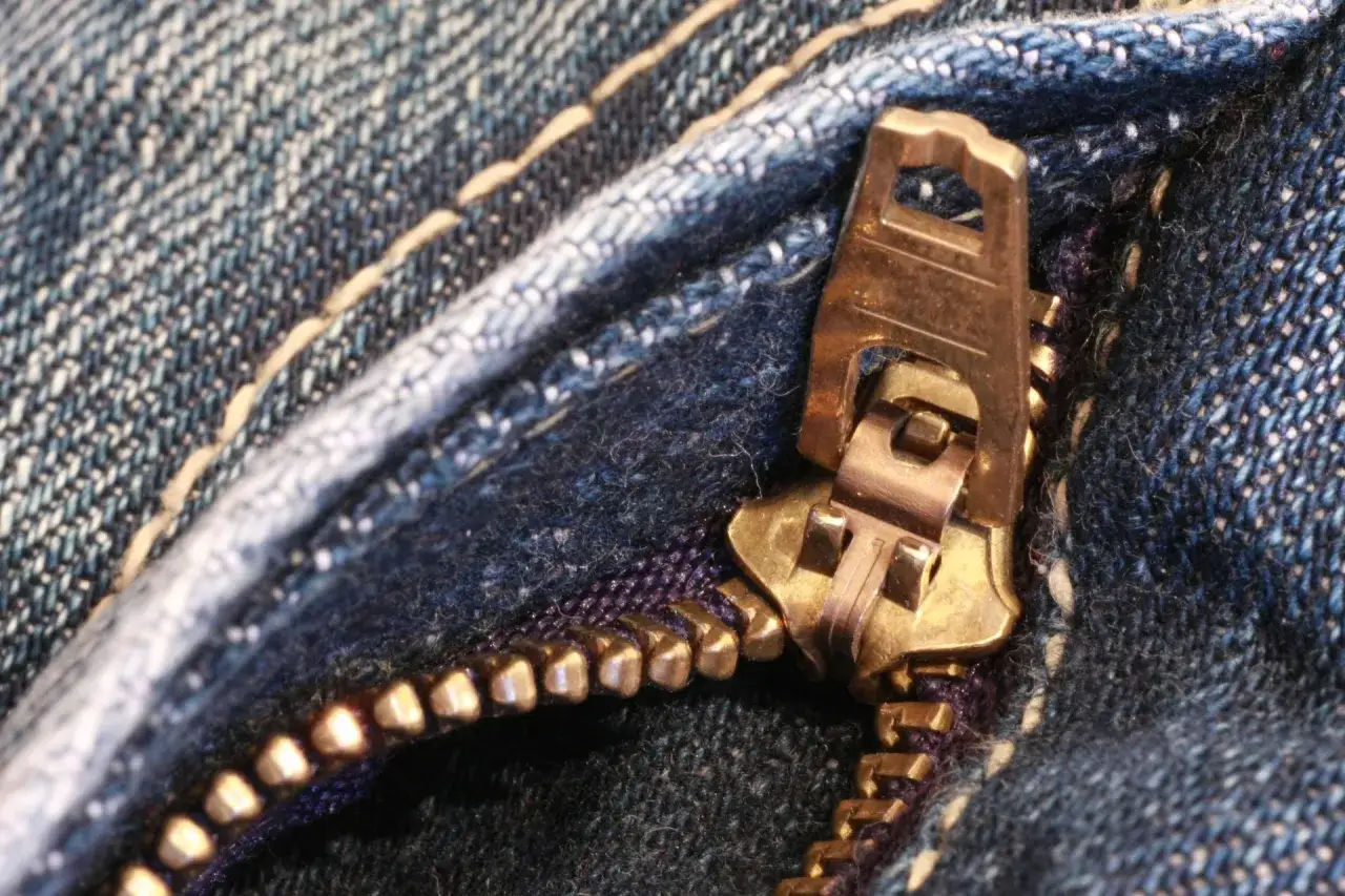 Złoty suwak na dżinsach, przypominający o tym, kiedy wynaleziono zamek błyskawiczny.