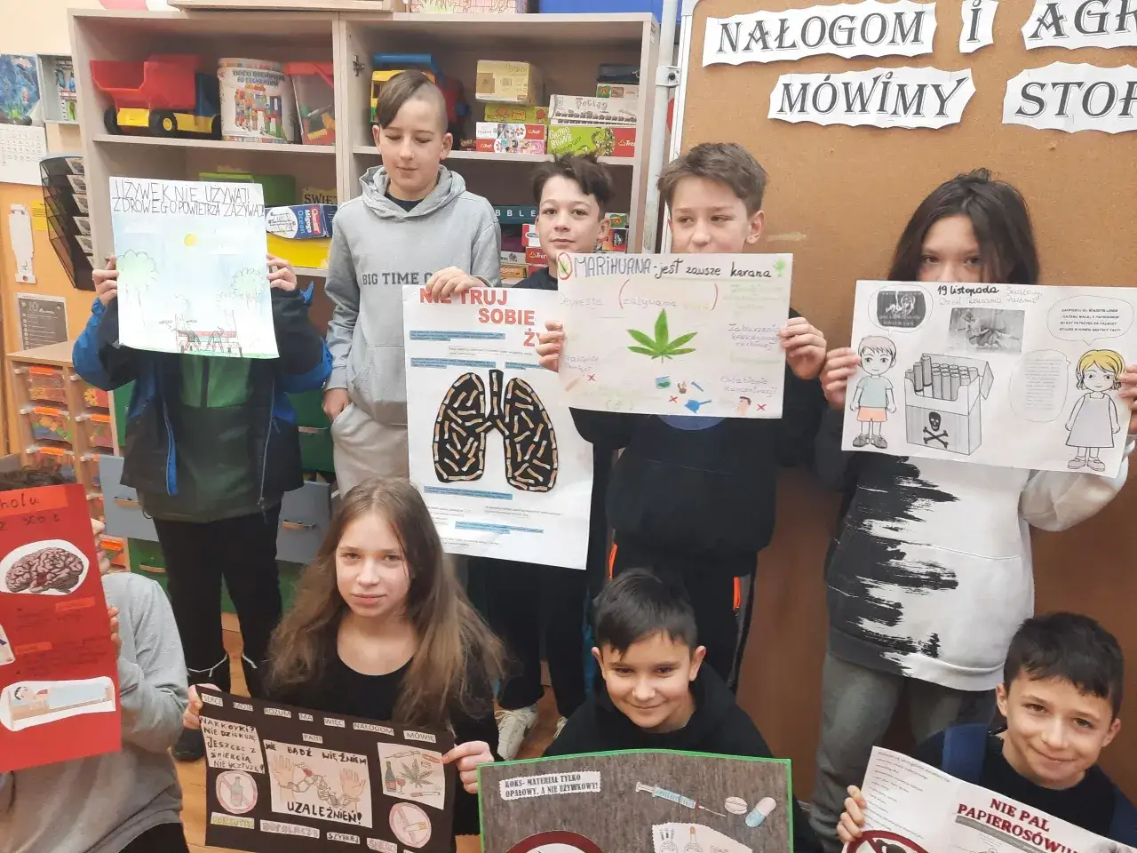 Dzieci trzymają plakaty o szkodliwości używek, m.in. o marihuanie i papierosach.