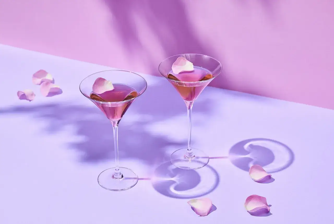 Elegancki French Martini przepis: dwa kieliszki z różowym drinkiem, ozdobione płatkami róż, na pastelowym tle.