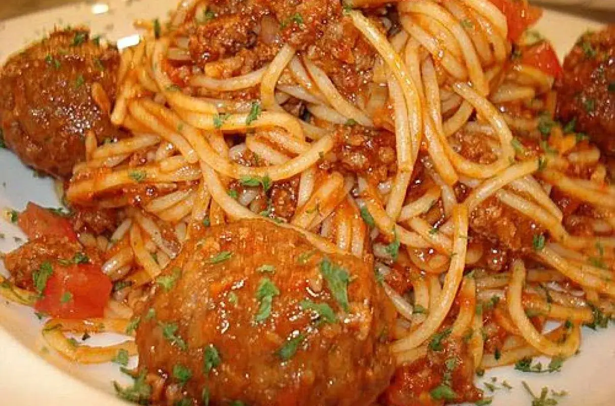 Pyszne spaghetti z pulpetami w sosie pomidorowym, posypane natką pietruszki. Klasyczne danie, które zawsze smakuje wyśmienicie.