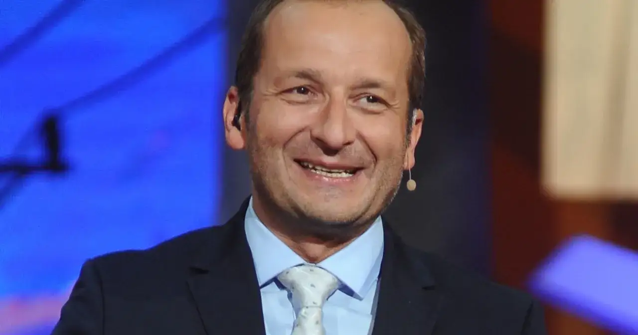 Uśmiechnięty Robert Górski z Kabaretu Moralnego Niepokoju w garniturze i jasnym krawacie.