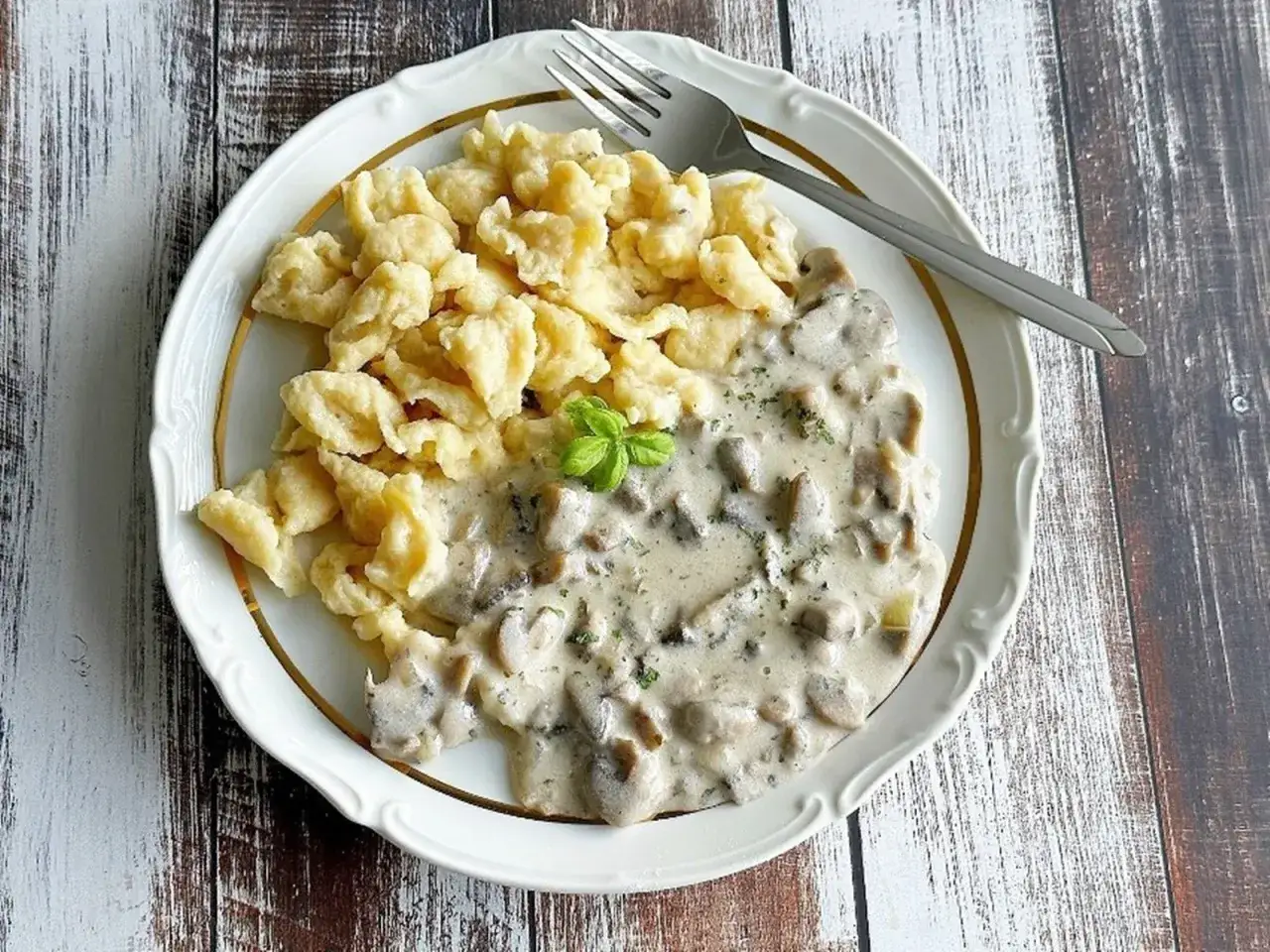 Pyszne kluski z sosem grzybowym – idealne co na obiad bez mięsa. Danie ozdobione listkiem bazylii.
