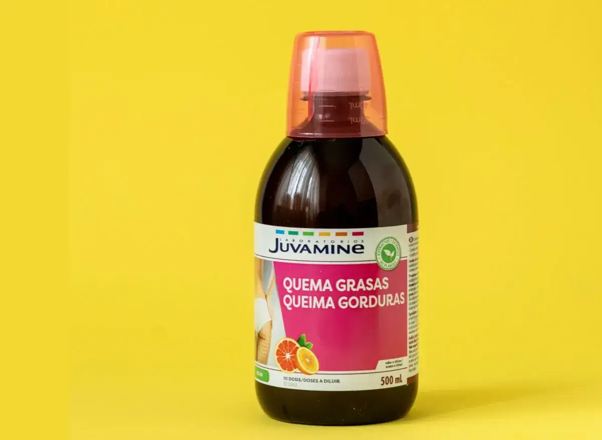 Botella de líquido quemagrasas con etiqueta rosa y naranja sobre fondo amarillo.