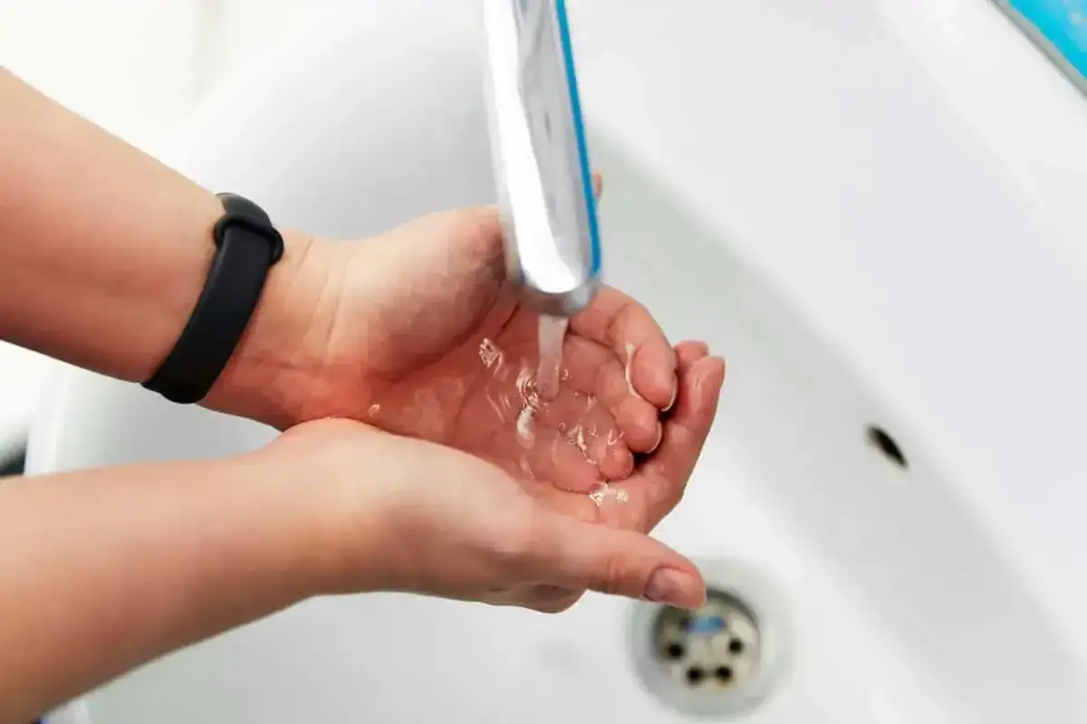 Dłonie pod bieżącą wodą z kranu. Zastanawiasz się, jak zwiększyć ciśnienie wody? Sprawdź nasze porady!