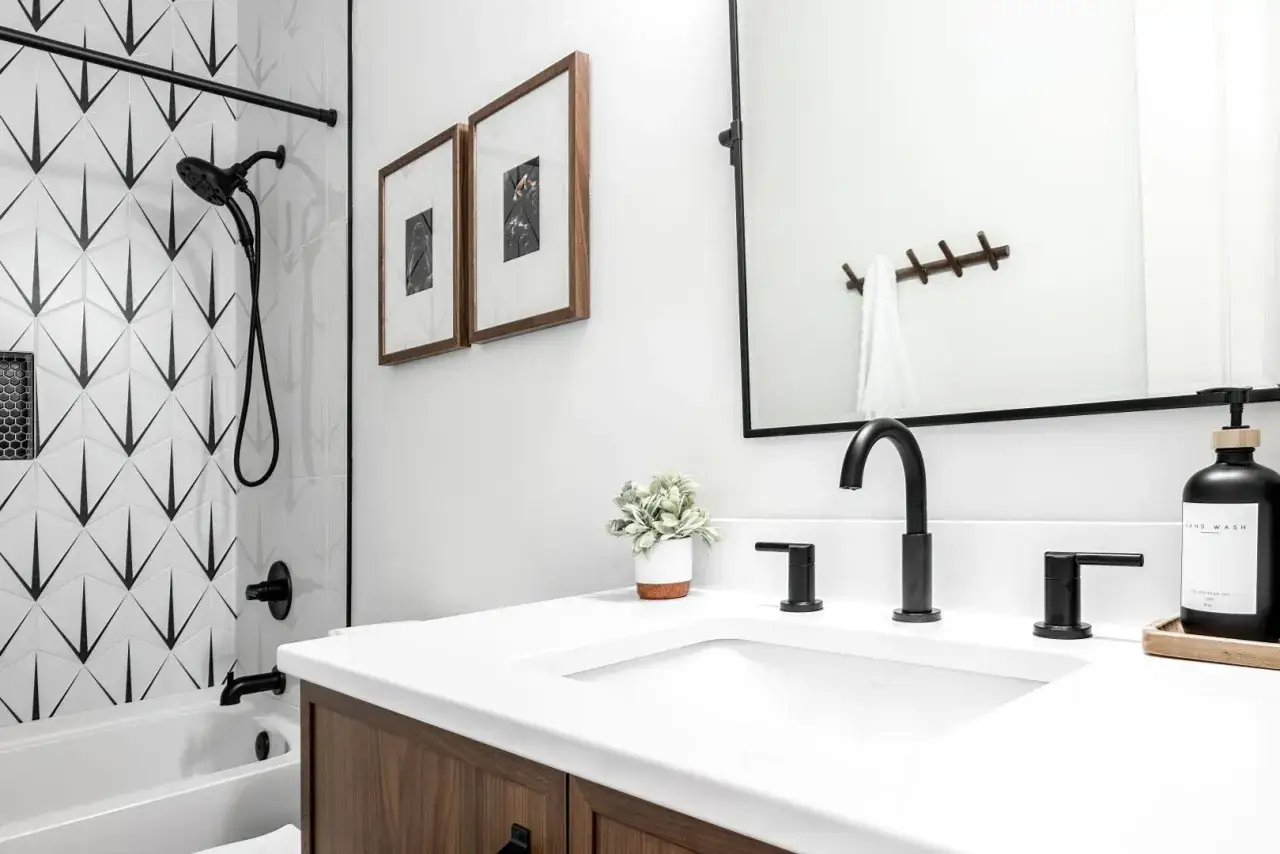 Nowoczesna łazienka z czarno-białymi panelami ściennymi, drewnianą szafką i czarną armaturą.