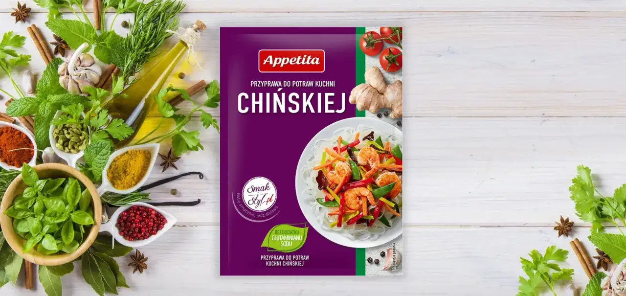 Opakowanie przyprawy do dań kuchni chińskiej Appetita. Obok świeże zioła, czosnek, imbir, pomidorki i składniki, jakie przyprawy do chińszczyzny.