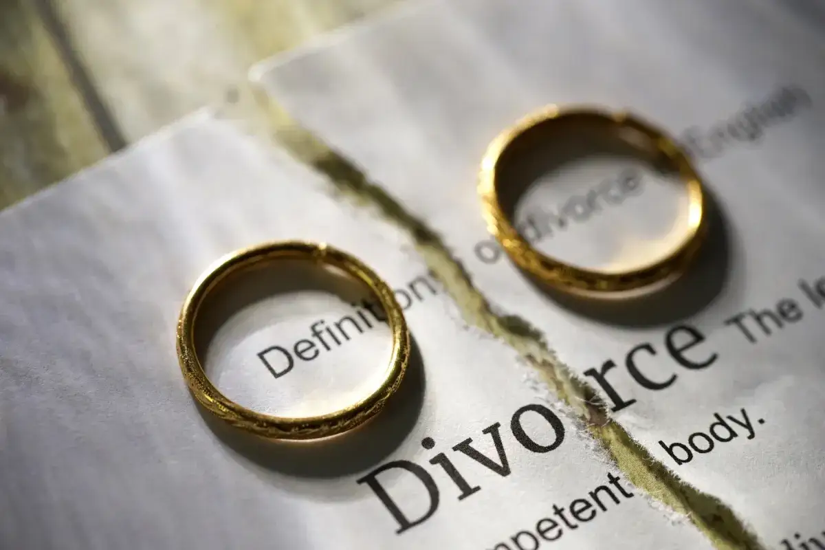 Dwa złote obrączki na przedartej kartce z napisem "Divorce".