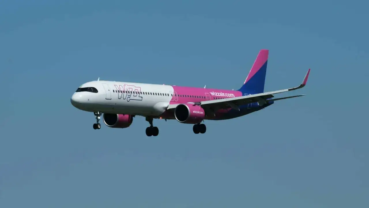 Samolot Wizz Air z wysuniętym podwoziem na tle błękitnego nieba.