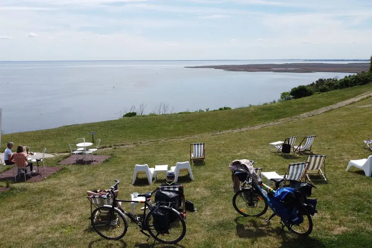 Ustronie Morskie trasa rowerowa z widokiem na morze. Dwa rowery turystyczne zaparkowane obok stolików i leżaków na trawie.