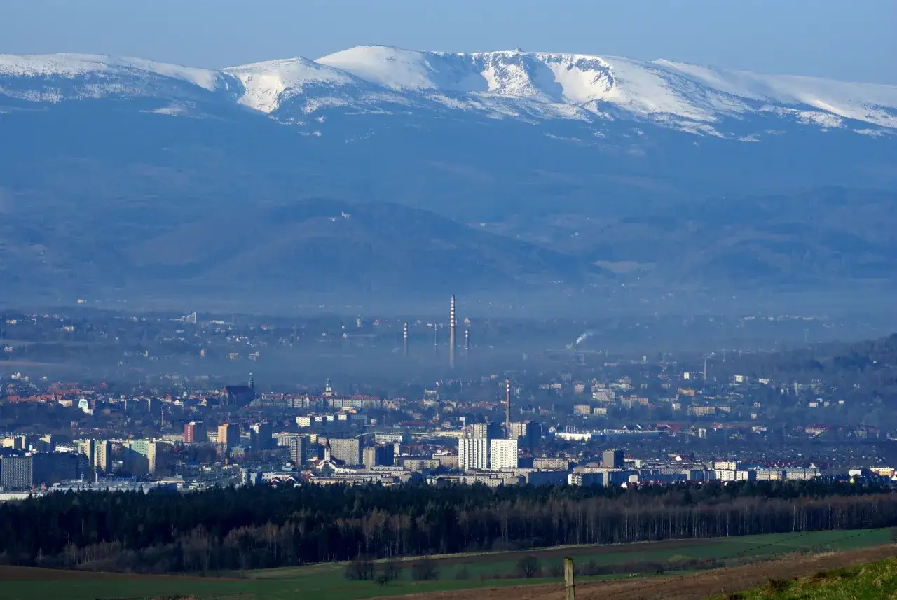 Widok na miasto u podnóża ośnieżonych gór. Trudno oszacować, ile jelenia góra ma mieszkańców, ale miasto jest spore.