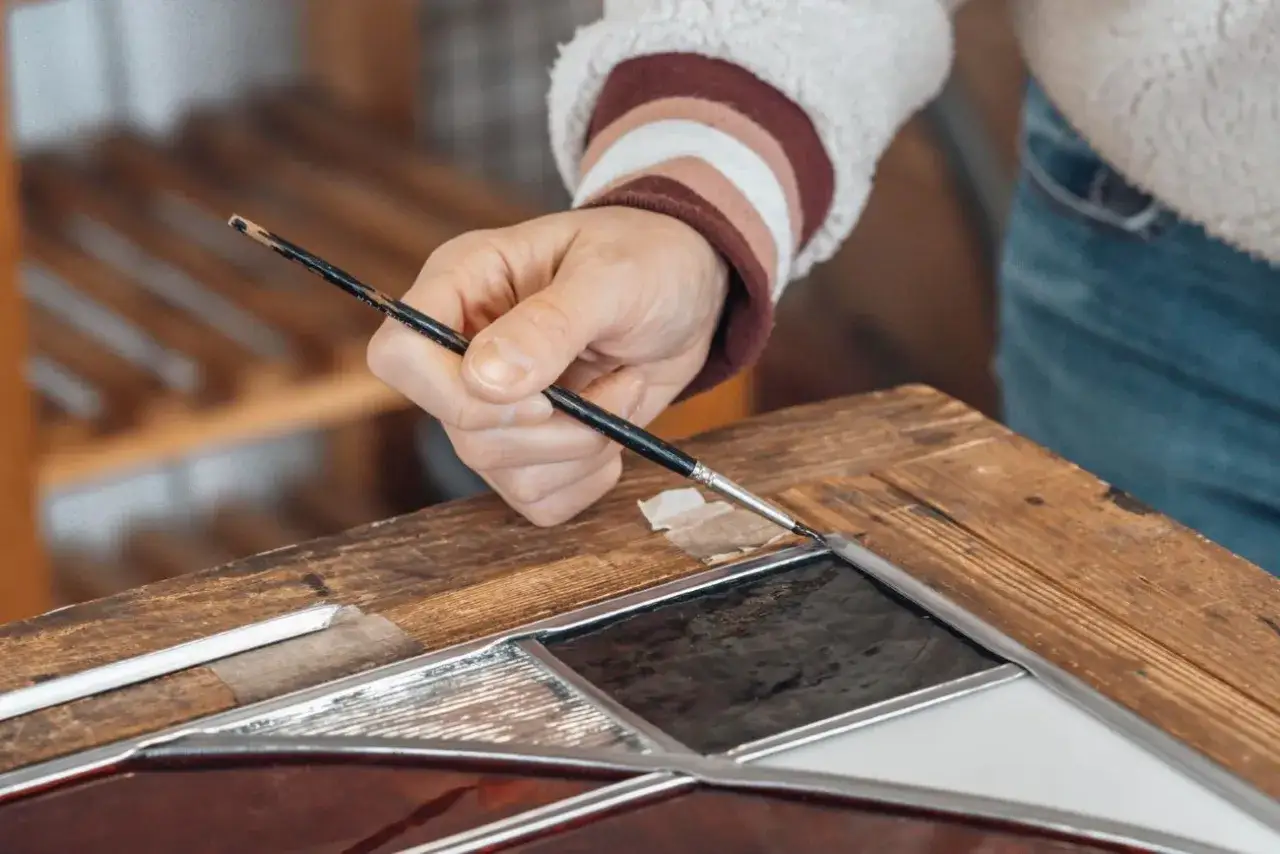 Odnawianie starych futryn drewnianych: precyzyjne malowanie pędzlem detali witrażowych.