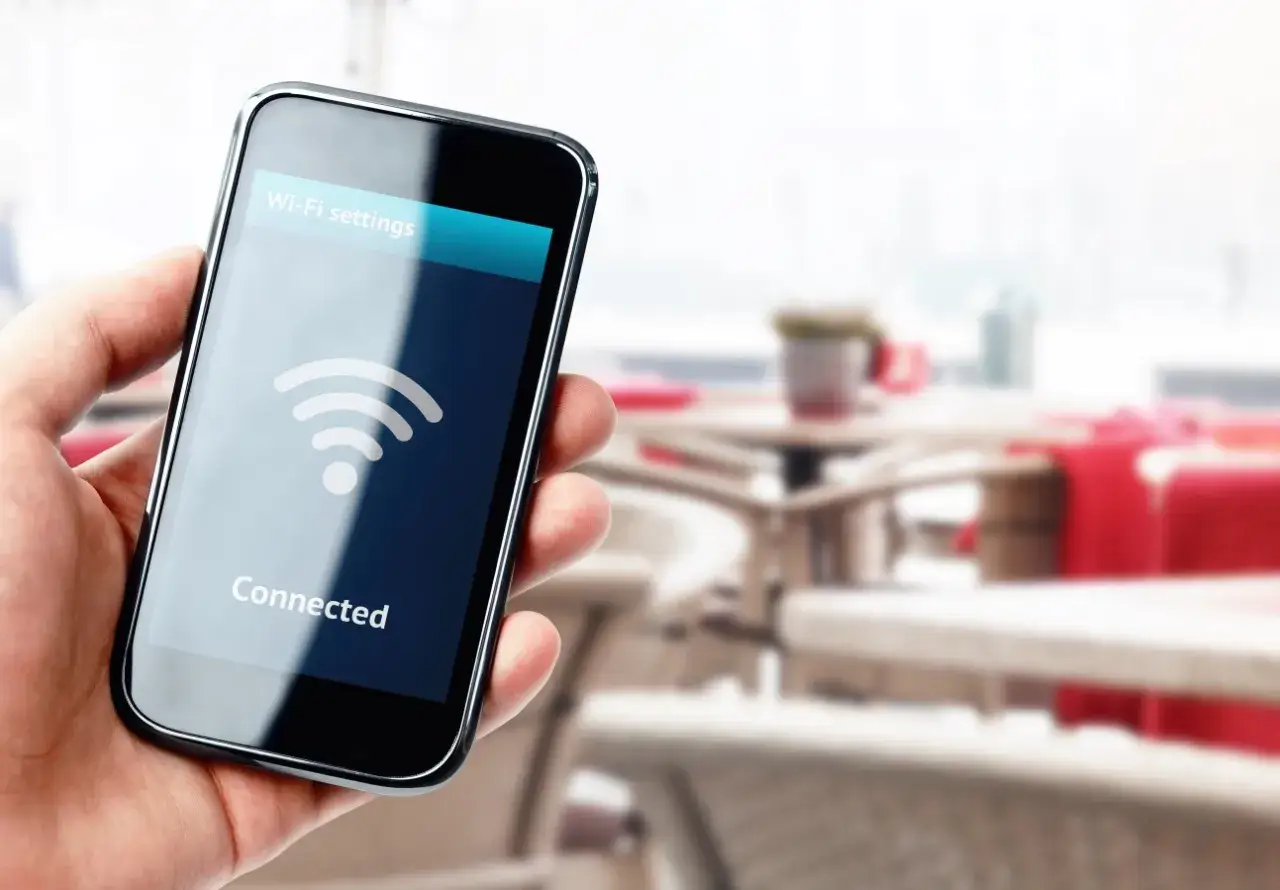 Dłoń trzyma smartfon z ikoną Wi-Fi i napisem "Connected".