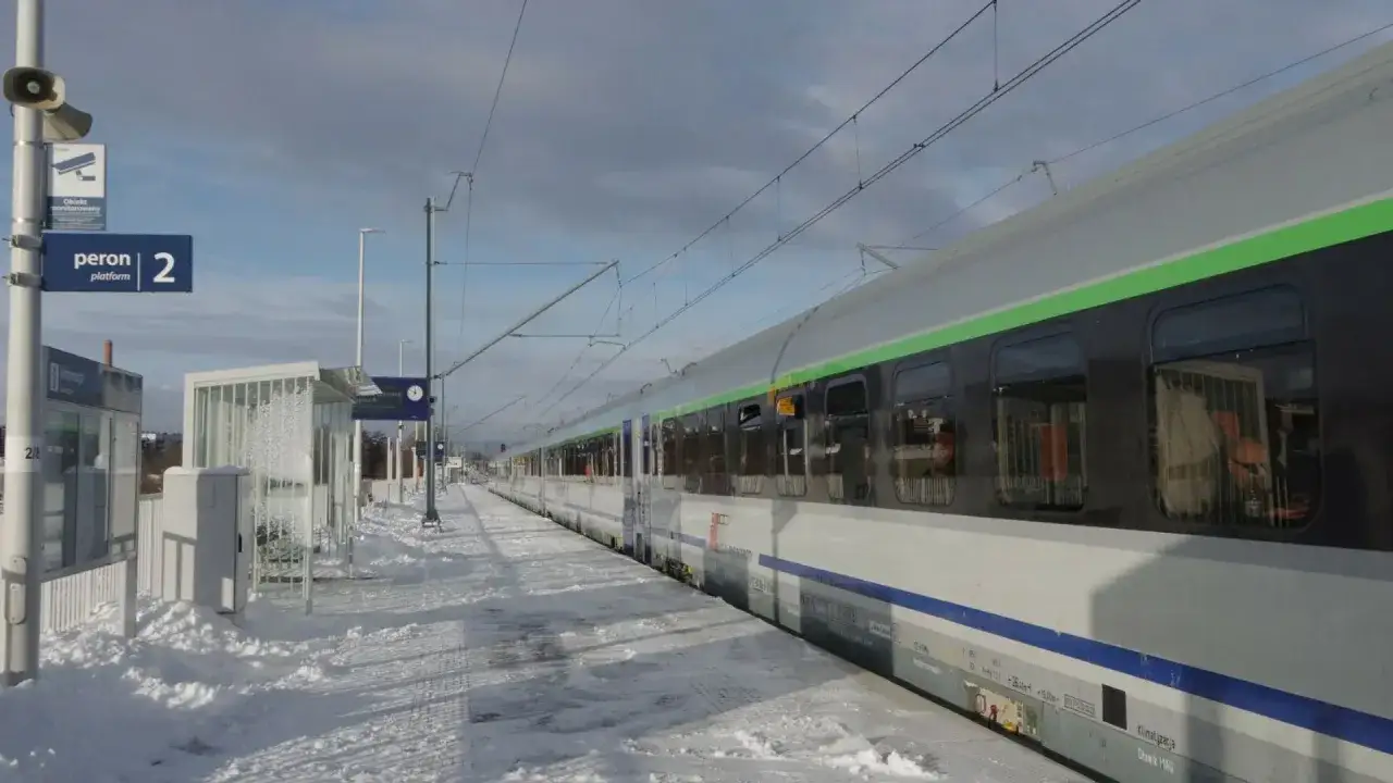 Zimowy peron 2, śnieg i pociąg do Krakowa czekają na pasażerów.