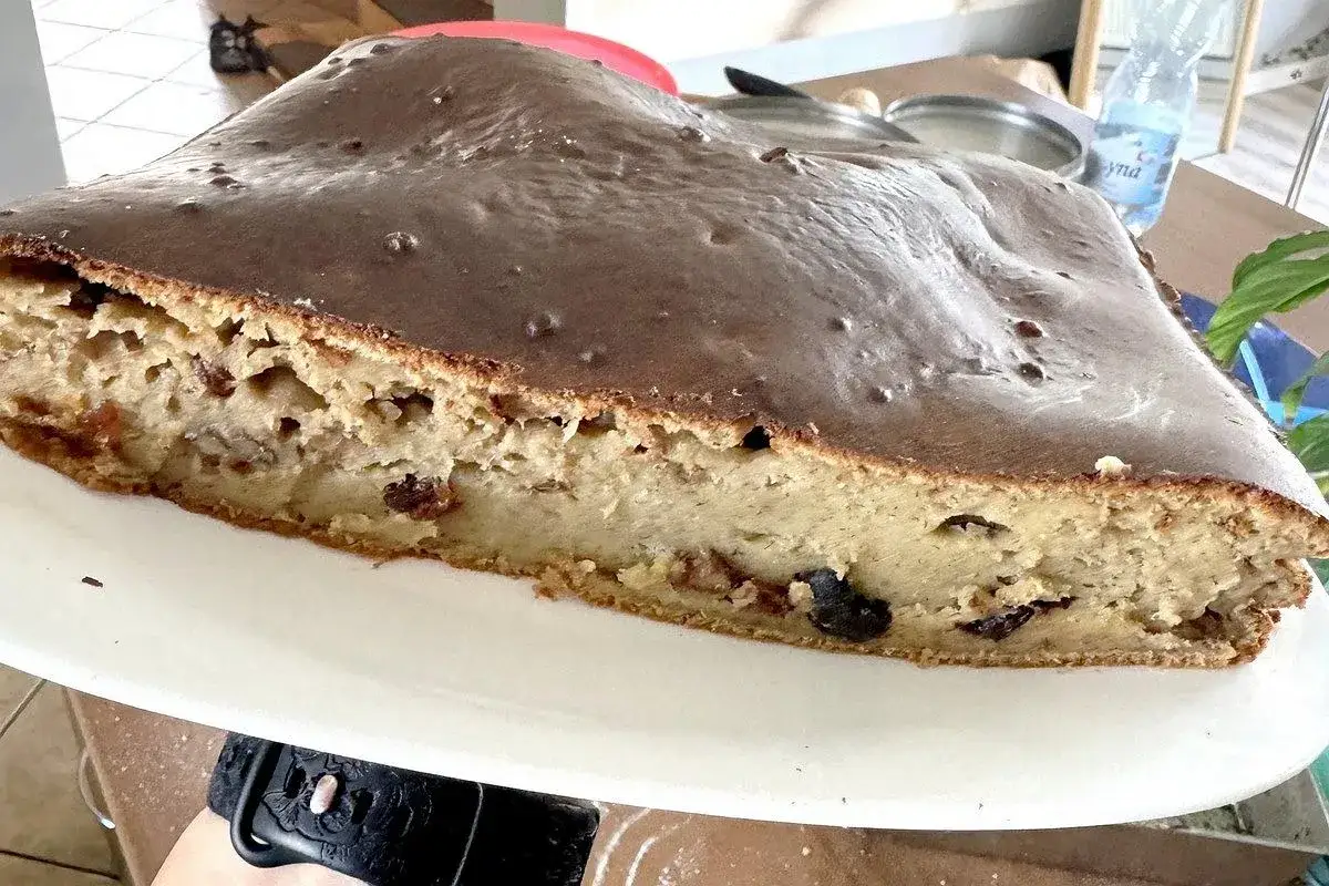 Sernik z polewą czekoladową, który opadł. Widać jego wilgotne wnętrze z bakaliami. Zastanawiasz się, dlaczego sernik opada?