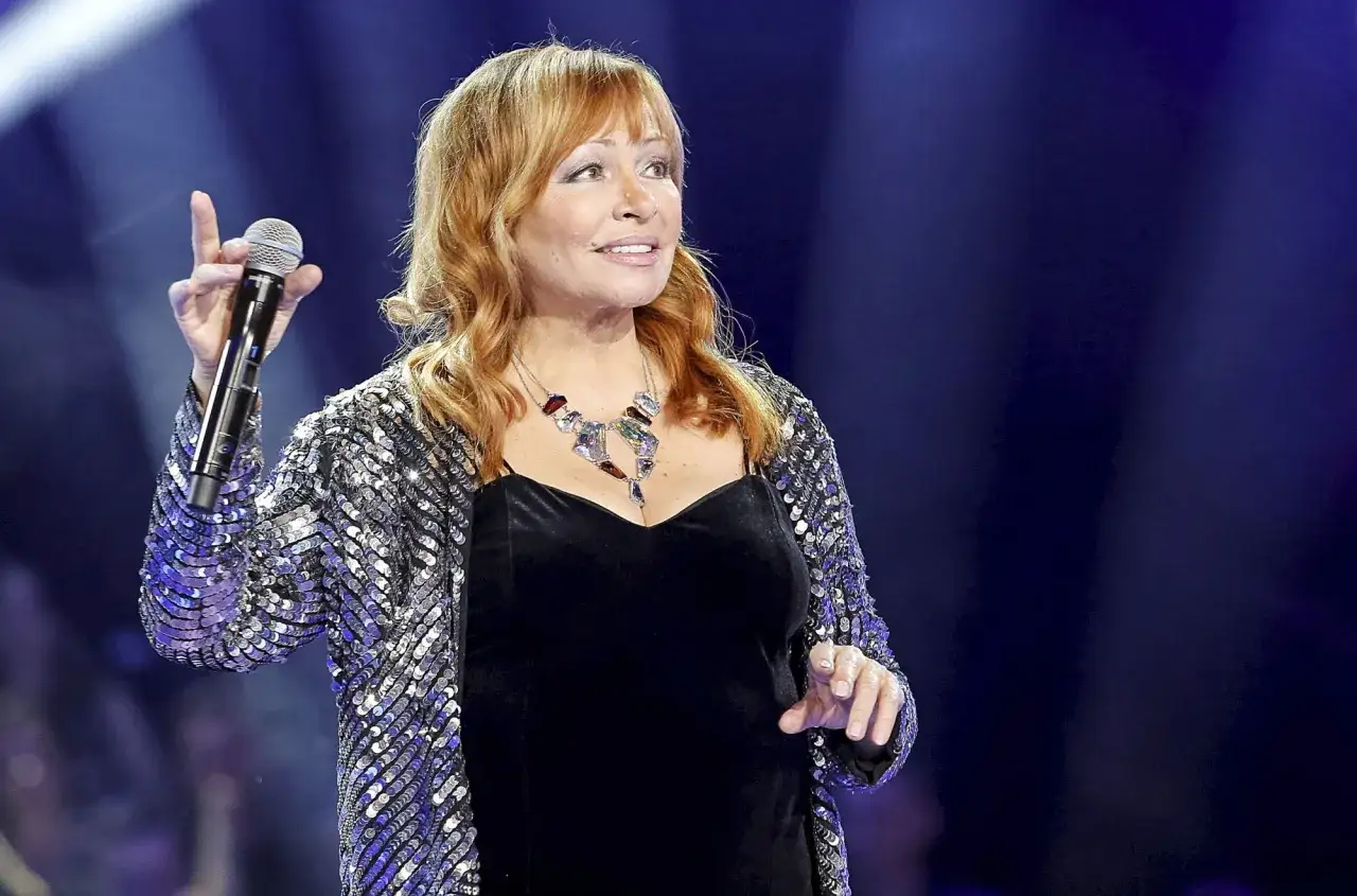 Kobieta w błyszczącej marynarce śpiewa na scenie. Czy to ona na alei gwiazd, kto śpiewa?