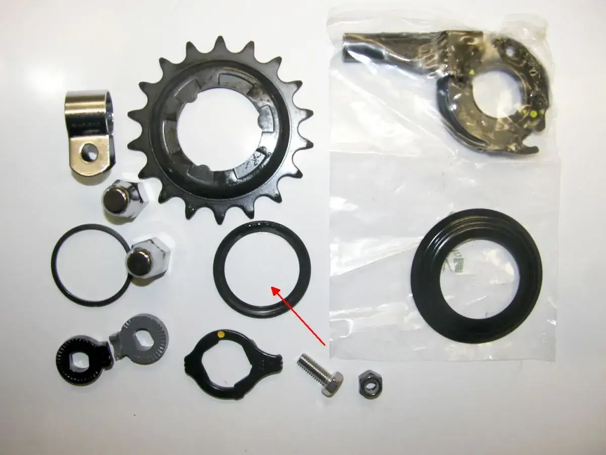 Zestaw części do naprawy przerzutki w piaście: zębatka, nakrętki, uszczelki, mechanizm i śruba.