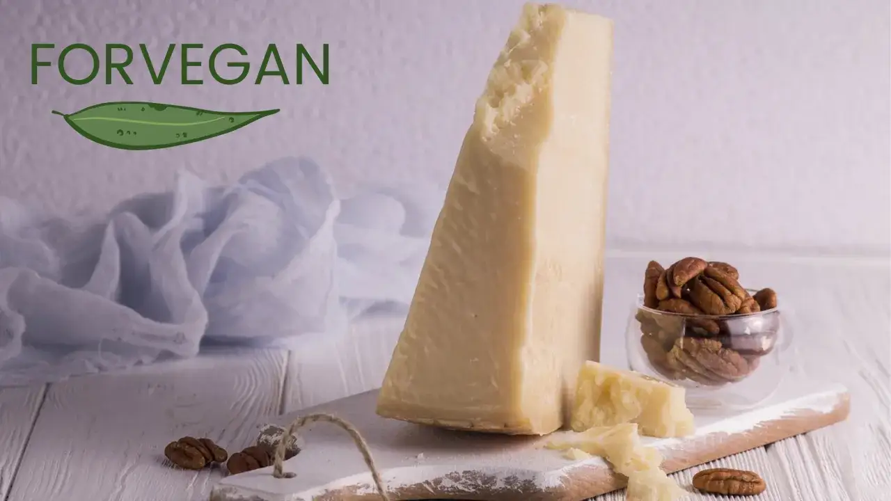 Kawałek sera parmezan, orzechy pekan w szklanej miseczce i liść z napisem FORVEGAN.