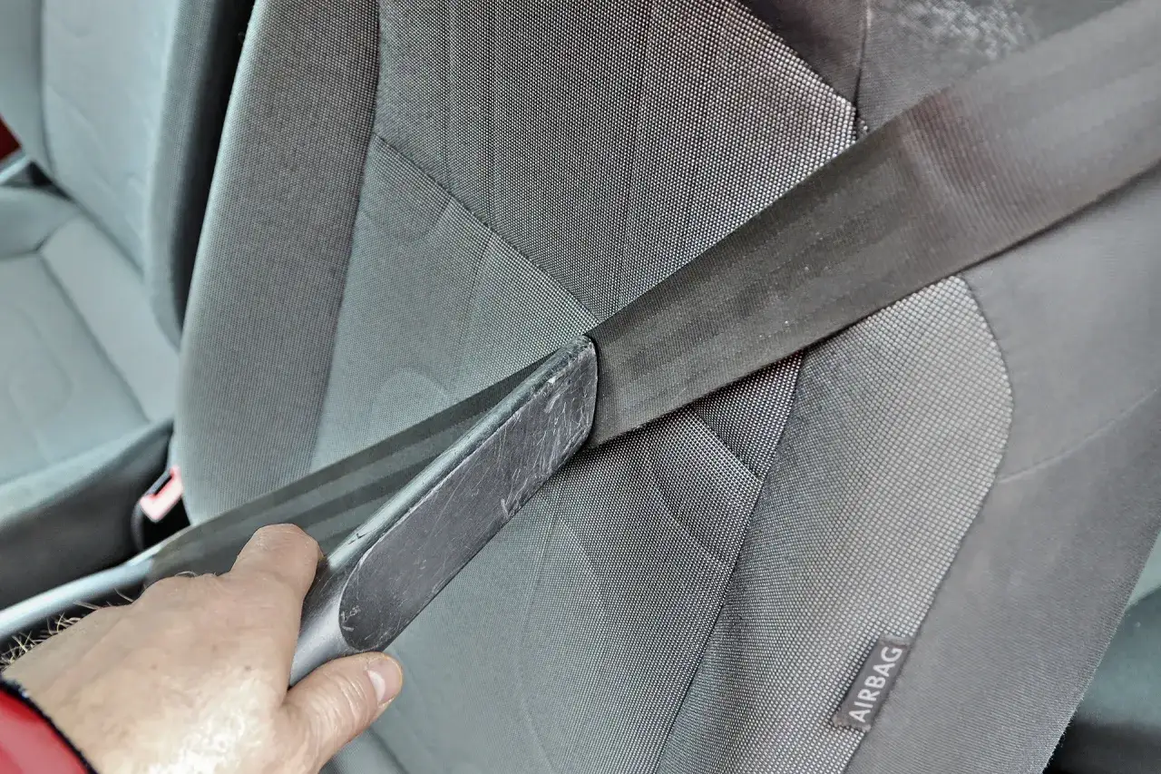 Dłoń trzyma narzędzie, które może pomóc w naprawie zwijacza pasów bezpieczeństwa w samochodzie.
