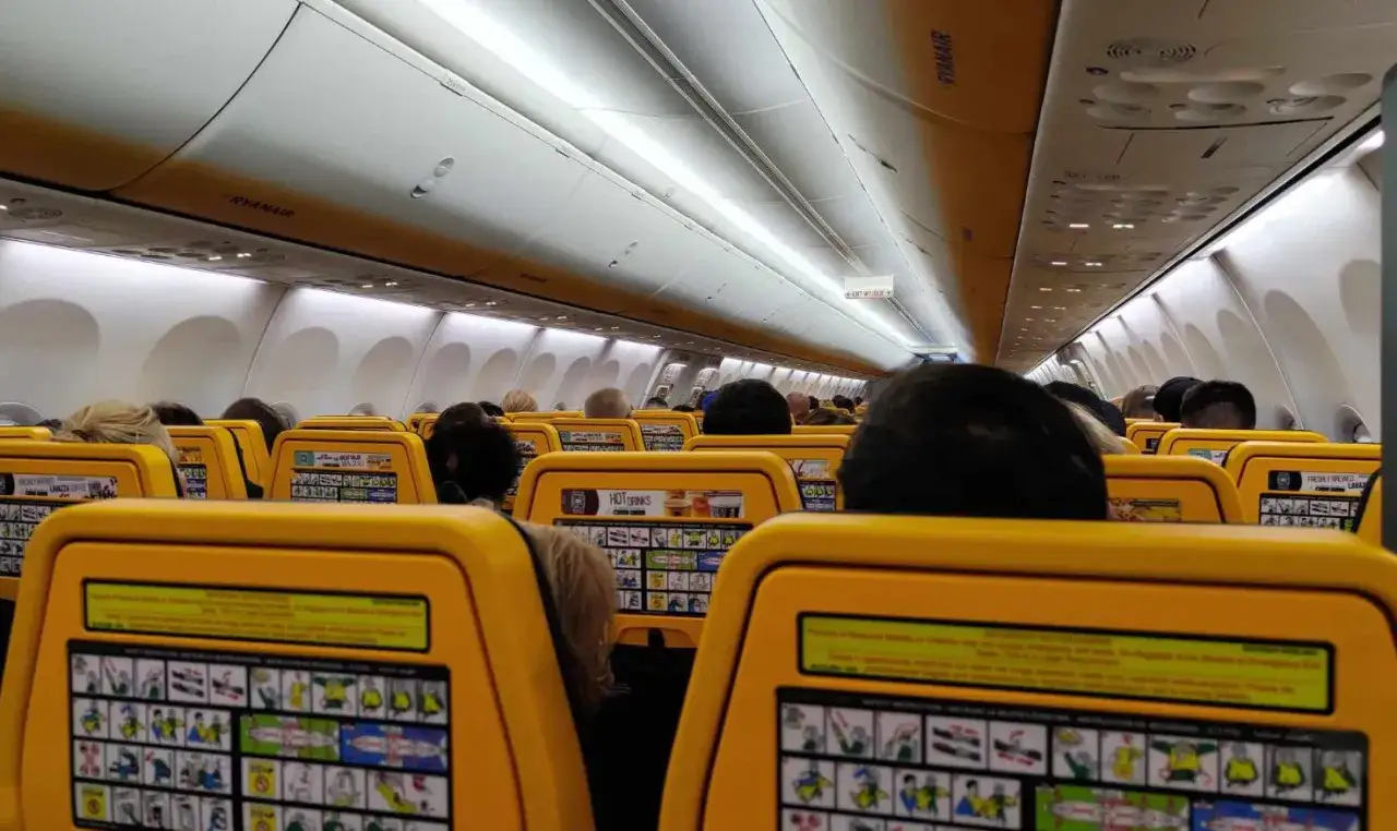 Widok wnętrza samolotu Ryanair z żółtymi siedzeniami i instrukcjami bezpieczeństwa.