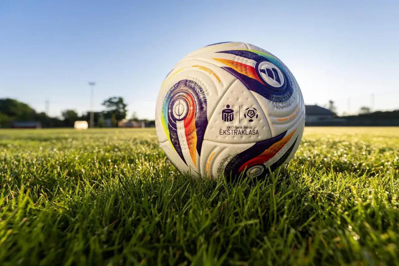 Piłka PKO Bank Polski Ekstraklasa leży na mokrej trawie. Ile meczy zostalo w ekstraklasie?