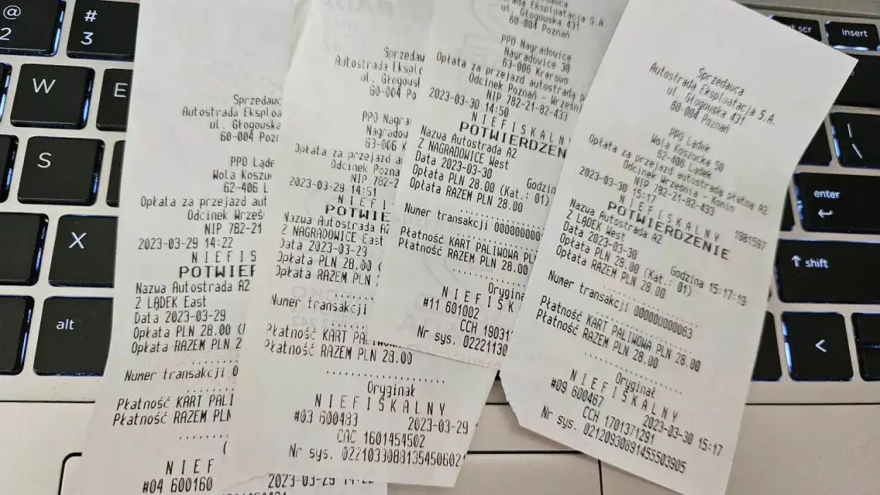 Paragon fiskalny z autostrady A2 na klawiaturze laptopa.