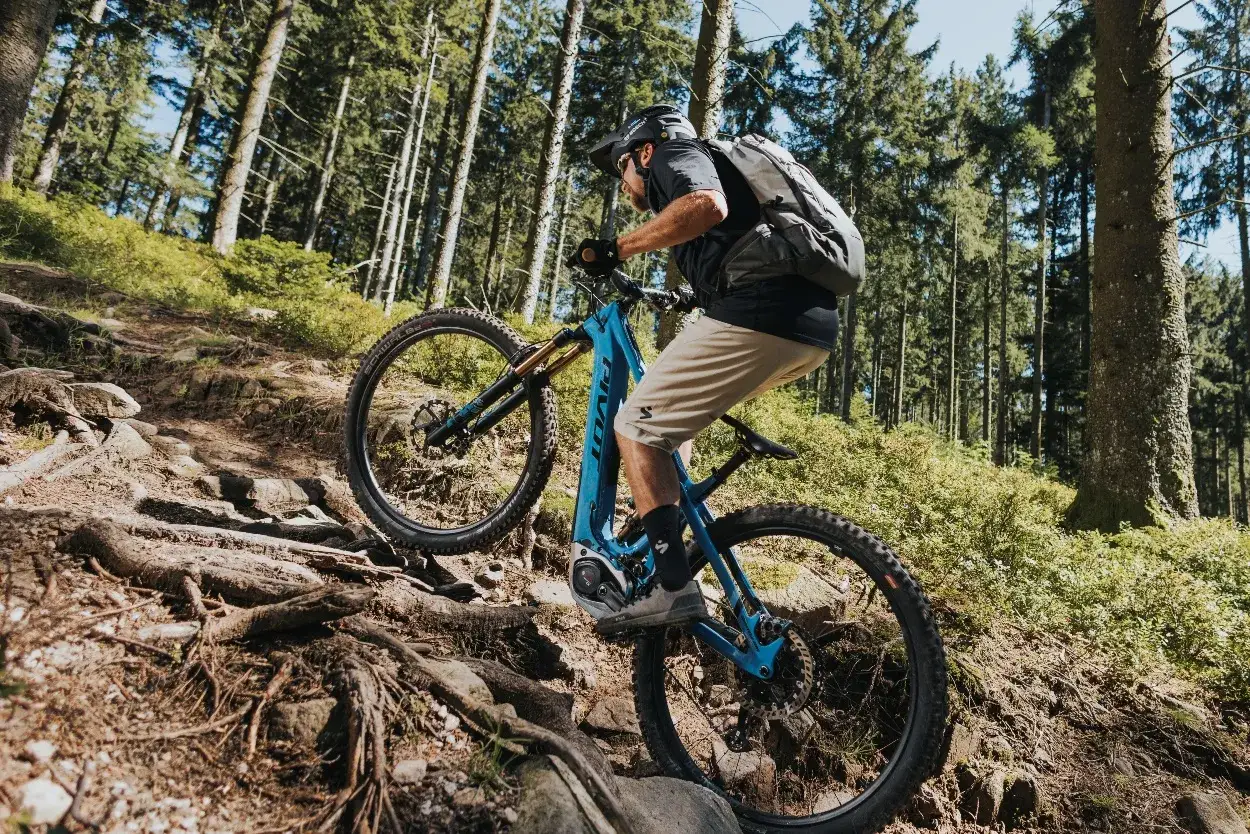 Kolarz na rowerze elektrycznym z napędem Bosch Performance Line CX pokonuje kamienisty, leśny szlak.