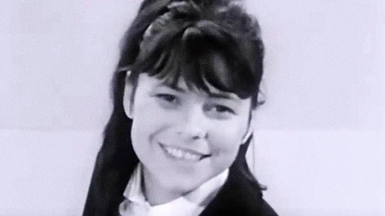 Uśmiechnięta Karin Stanek, jak malowana lala, w czarnym żakiecie i białej koszuli.