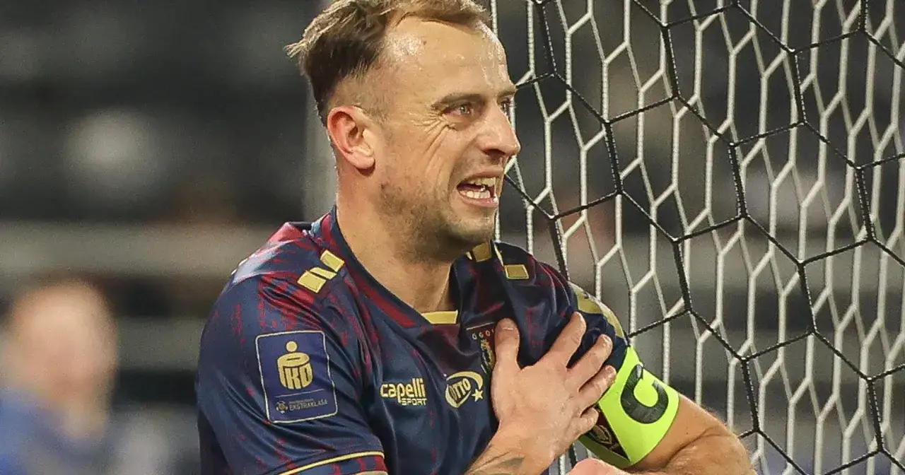 Piłkarz Pogoni Szczecin z opaską kapitana, zaciśniętą pięścią na ramieniu, w geście frustracji. Czy to odzwierciedla jego zarobki?