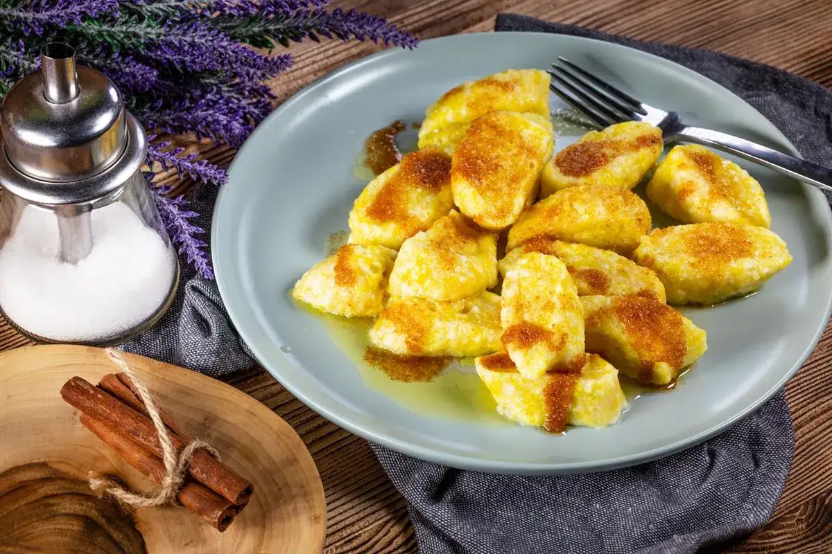 Pyszne kopytka na obiad, polane masłem z bułką tartą. Obok cukiernica, cynamon i lawenda.