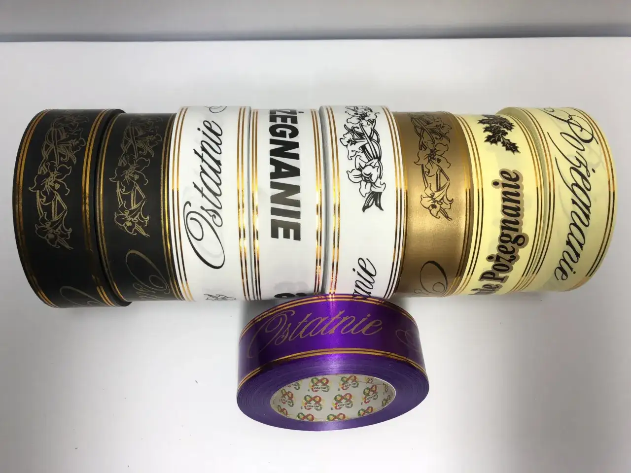 Szarfy pogrzebowe w różnych kolorach i z napisami, w tym fioletowa na pierwszym planie.