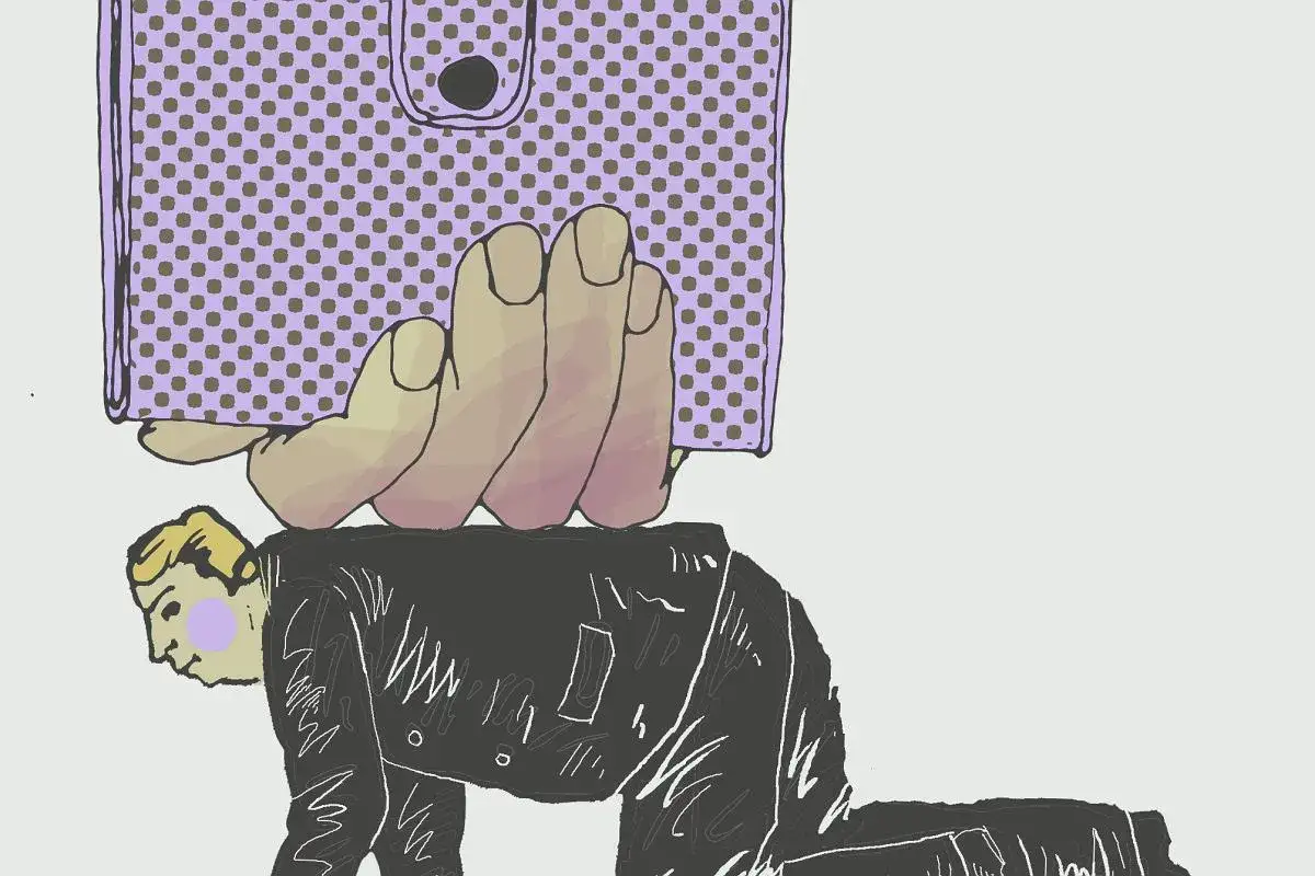 Dłoń z portfelem przygniata mężczyznę w garniturze. Czy to symbol tego, ile zarabia doktor na uczelni?