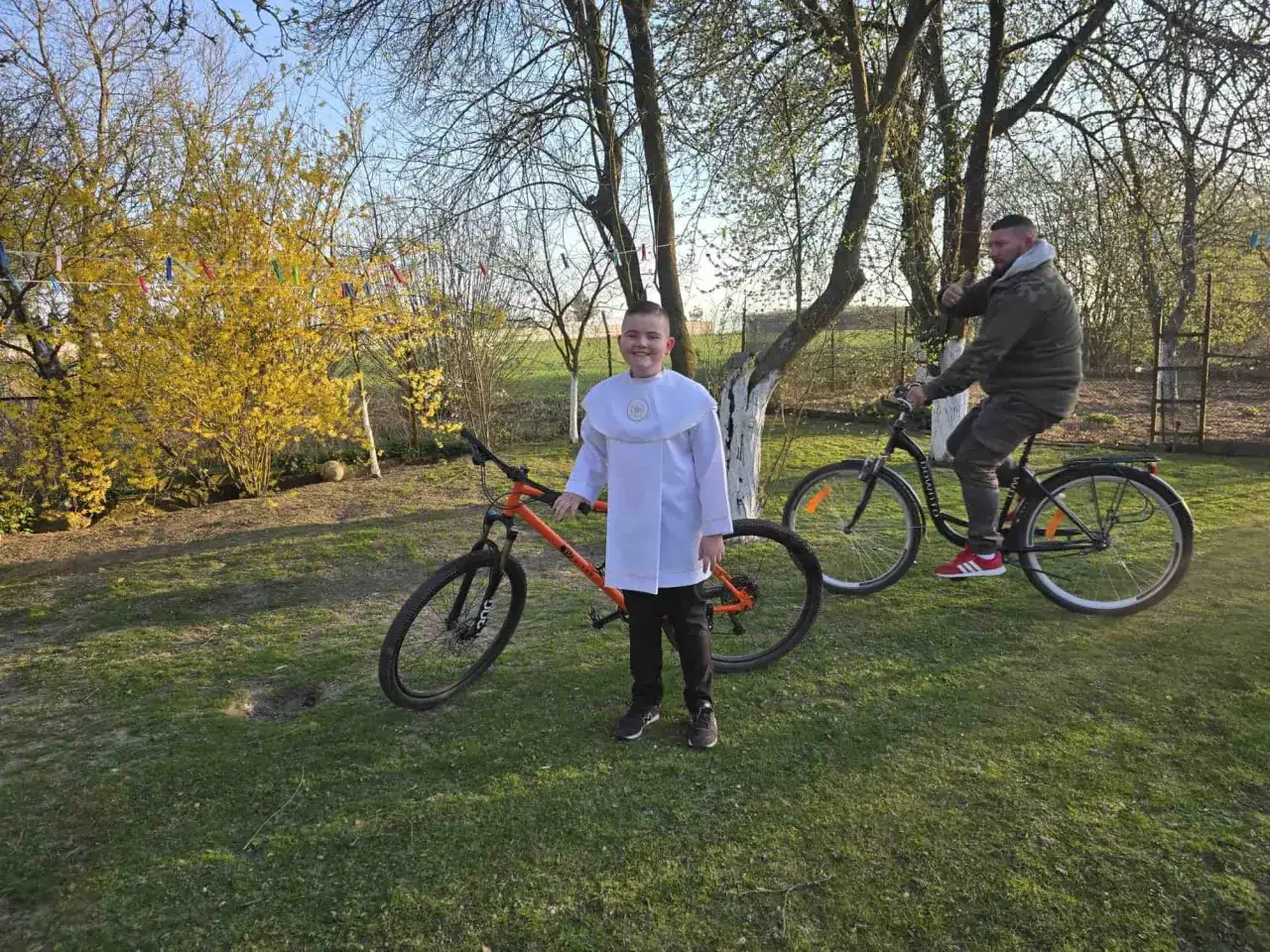 Chłopiec w albie i mężczyzna na rowerach. Pomarańczowy rower 29 cali na jaki wzrost?